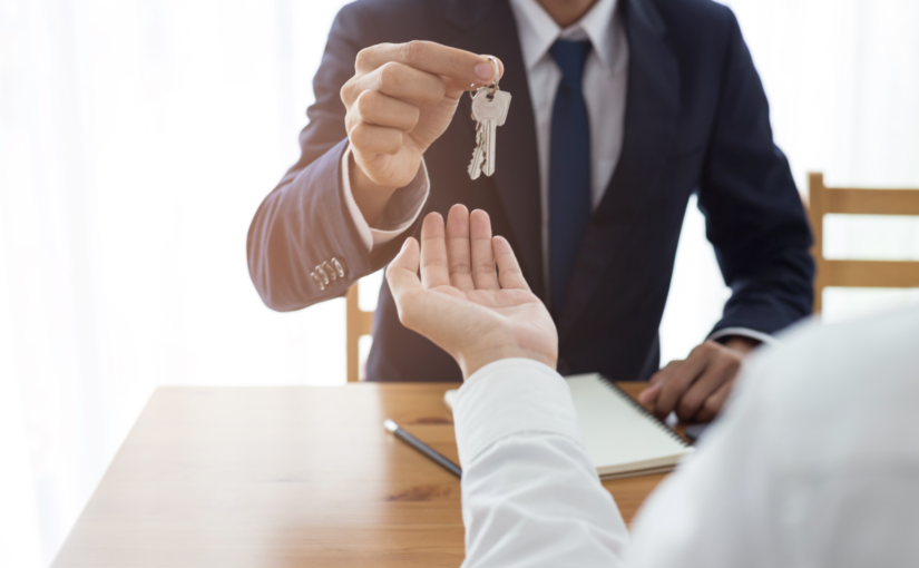 a man in a suit handing a key to a woman